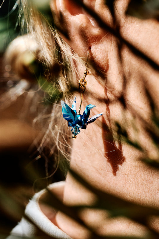 Close-up of a person wearing a blue crystal earring with a blurred background