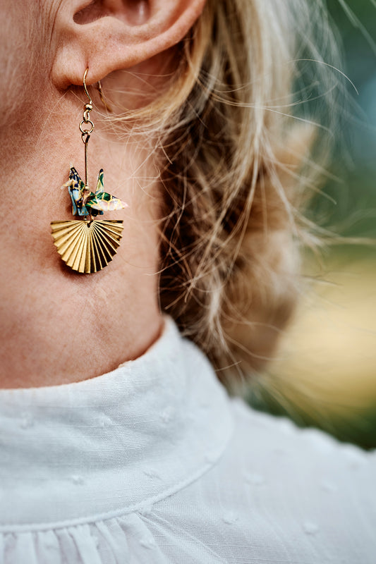 Close-up of a gold earring with a decorative design worn by a person.