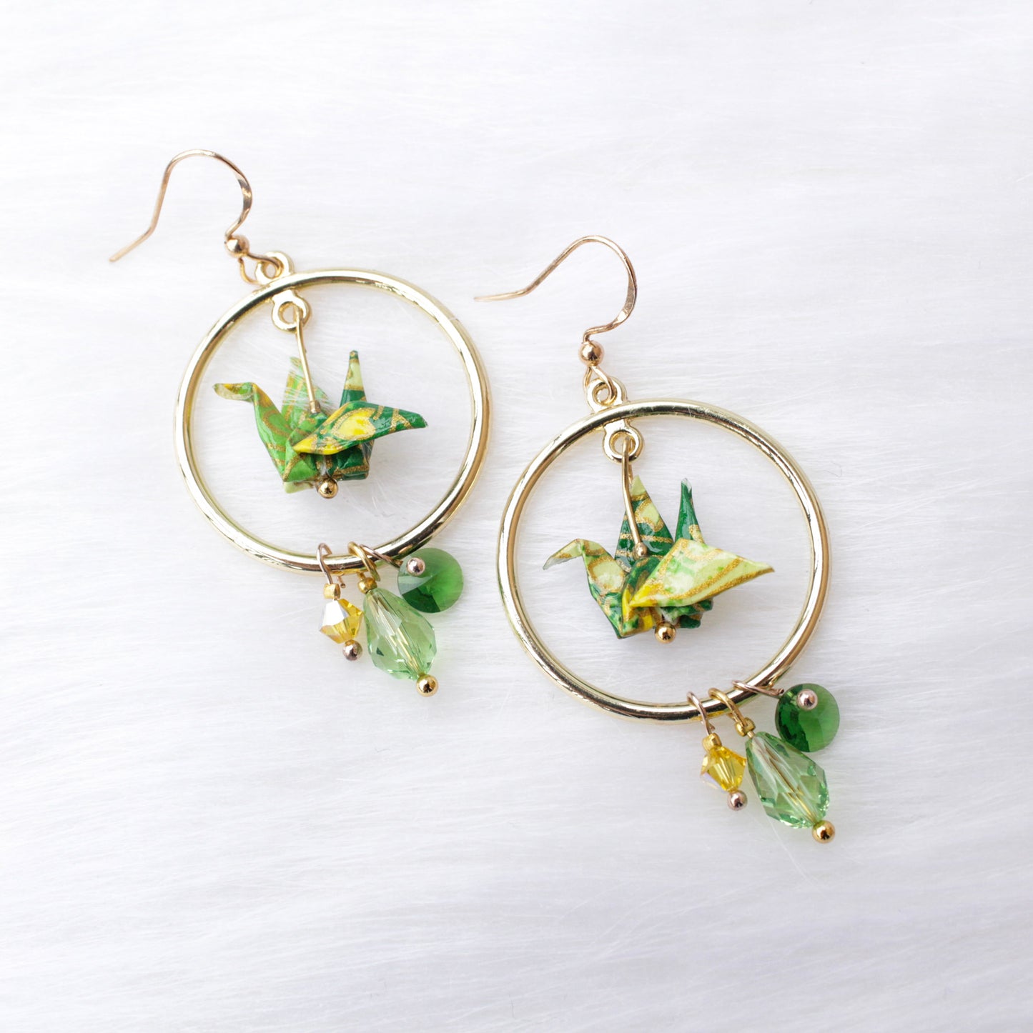 A pair of origami crane earrings with blue and multicolored accents, adorned with sparkling Swarovski crystals, suspended from silver hooks.