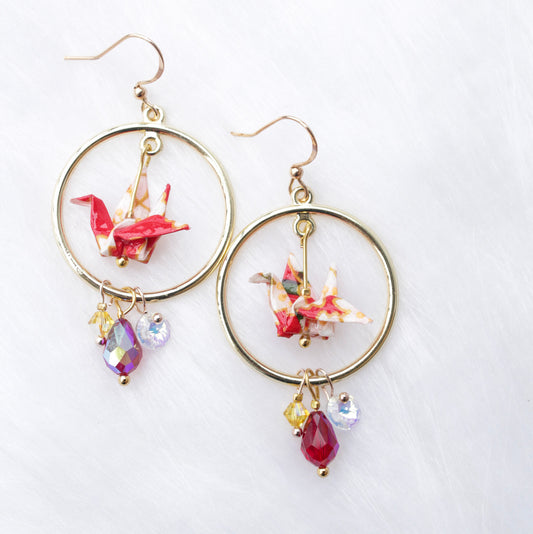 A pair of origami crane earrings with blue and multicolored accents, adorned with sparkling Swarovski crystals, suspended from silver hooks.